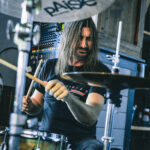 A man with long hair playing drums.