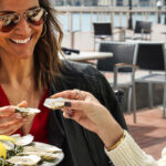 two women eating oysters at an outdoor restaurant.