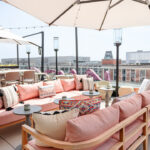 a patio with pink couches and umbrellas on top of it.