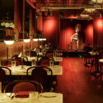 a room with tables and chairs and a red curtain.