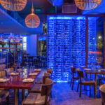 a restaurant with blue lighting and wooden tables.