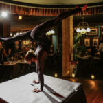 a woman doing a handstand on top of a table.