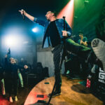 a man standing on top of a stage holding a microphone.