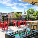 a foo - pong table on a patio with red chairs.