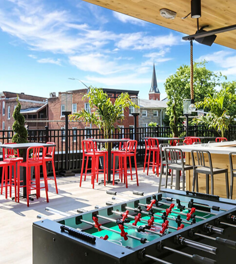 a foo - pong table on a patio with red chairs.
