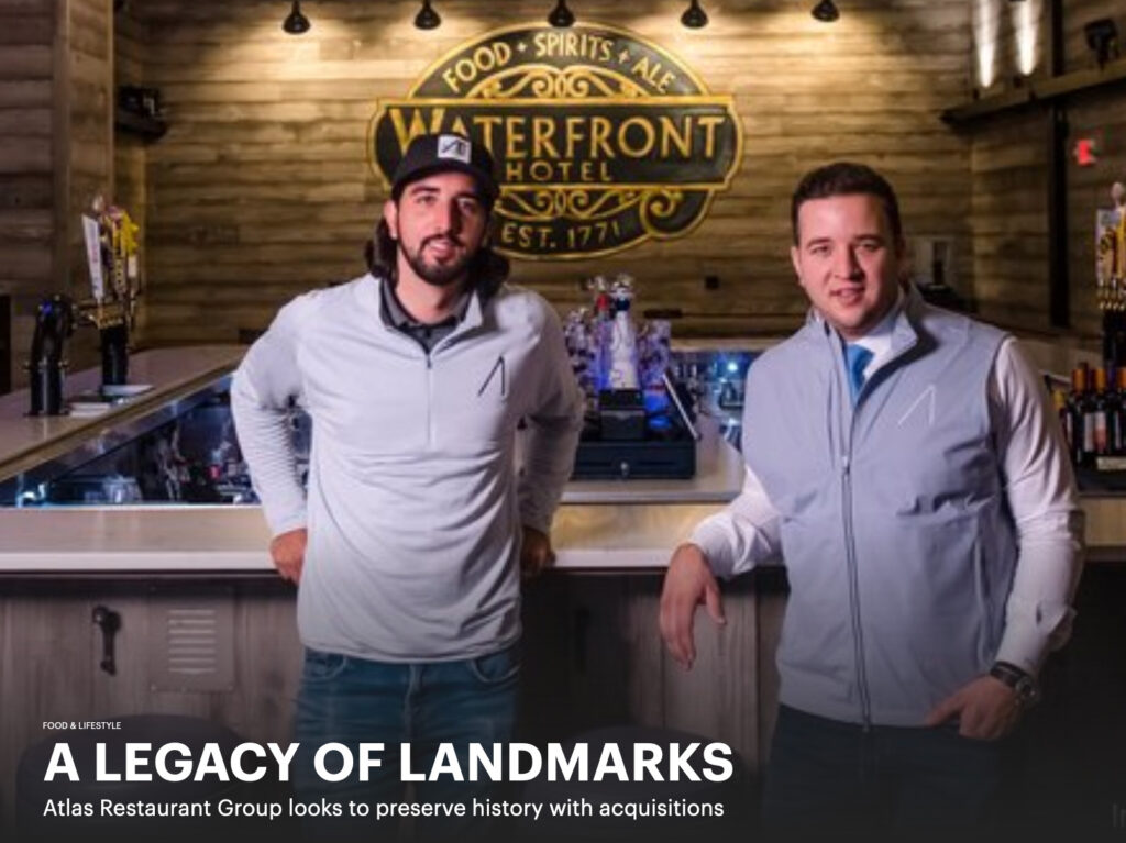 Two men standing in front of a bar with the words legacy of landmarks.