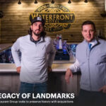 Two men standing in front of a bar with the words legacy of landmarks.